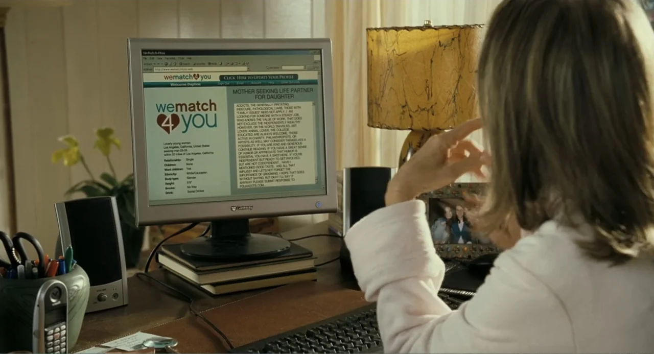 Because I Said So (2007) movie still: medium — A home office setting features a wooden desk with a computer monitor displaying text. A woman sits at…