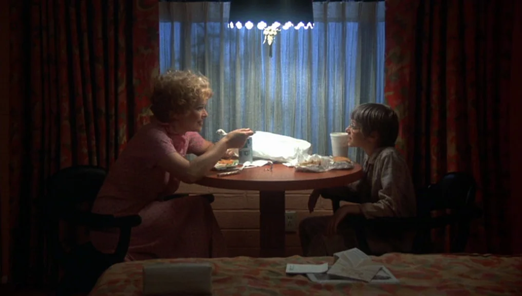 Alice Doesn’t Live Here Anymore (1974) movie still: medium — A motel room at night features red patterned curtains and a central dining table. A…