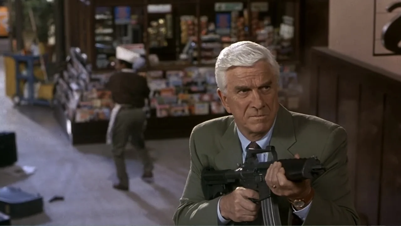 Naked Gun 33⅓: The Final Insult (1994) movie still: medium — An interior convenience store with shelves of merchandise and a tiled floor. A man with…