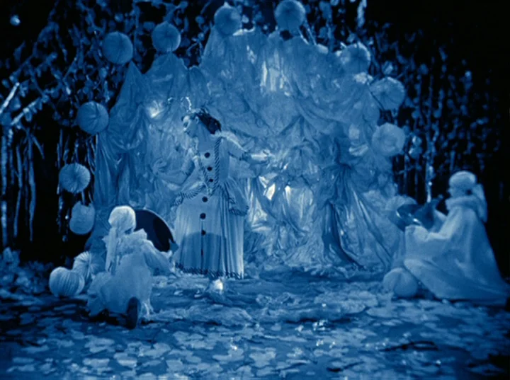 Rabbit’s Moon (1950) movie still: fullbody — A theatrical set is draped in layers of fabric and decorated with spherical ornaments. A central dancer…