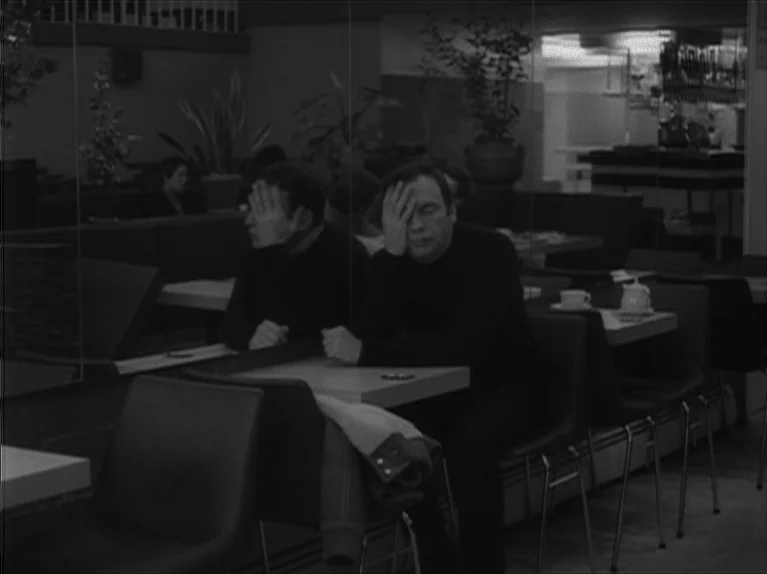 My Night At Maud’s (Ma Nuit Chez Maud) (1969) movie still: medium — A quiet cafeteria features tables and chairs arranged near a reflective wall…