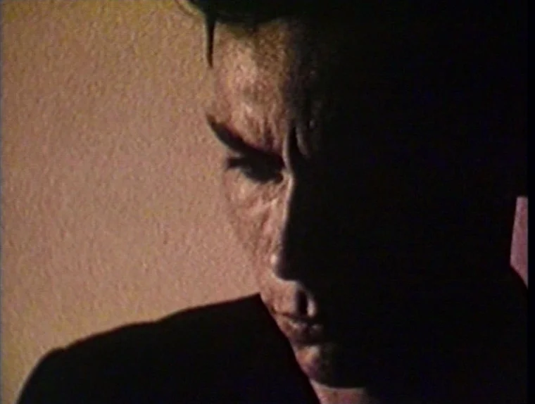 The Angelic Conversation (1985) movie still: closeup — A dimly lit room with plain wall surfaces visible behind the subject. A man is seen in…