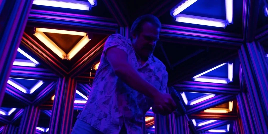 Stranger Things (2019) movie still: medium — A complex interior structure features repeating angular frames illuminated by bright orange and blue…