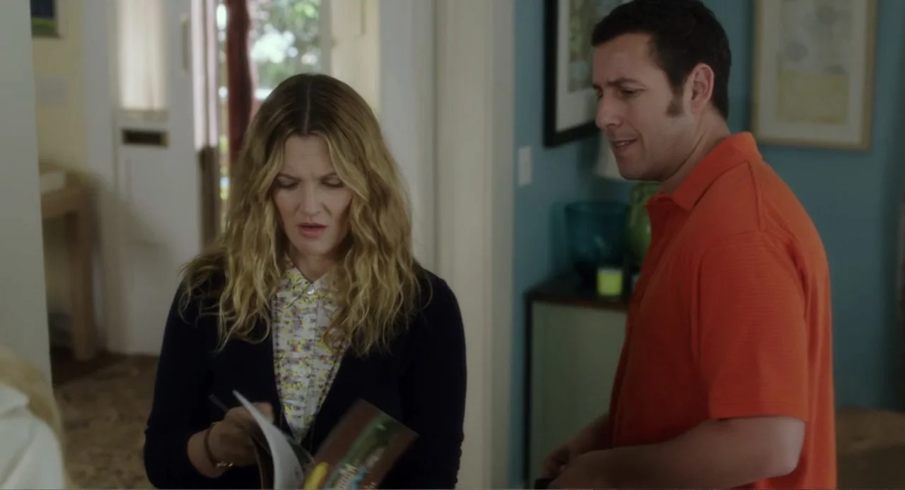 Blended (2014) movie still: medium — A residential interior features blue walls with framed artwork and a doorway leading outside. A woman examines…