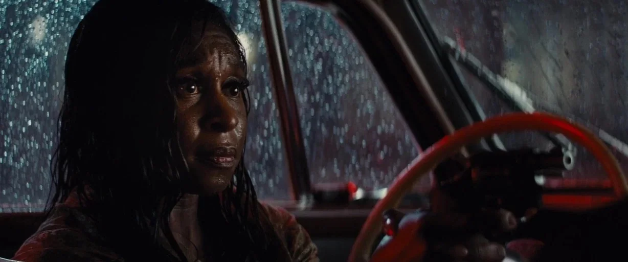 Bad Times at the El Royale (2018) movie still: closeup — The interior of a car at night during heavy rain. A woman drives while holding a handgun in…