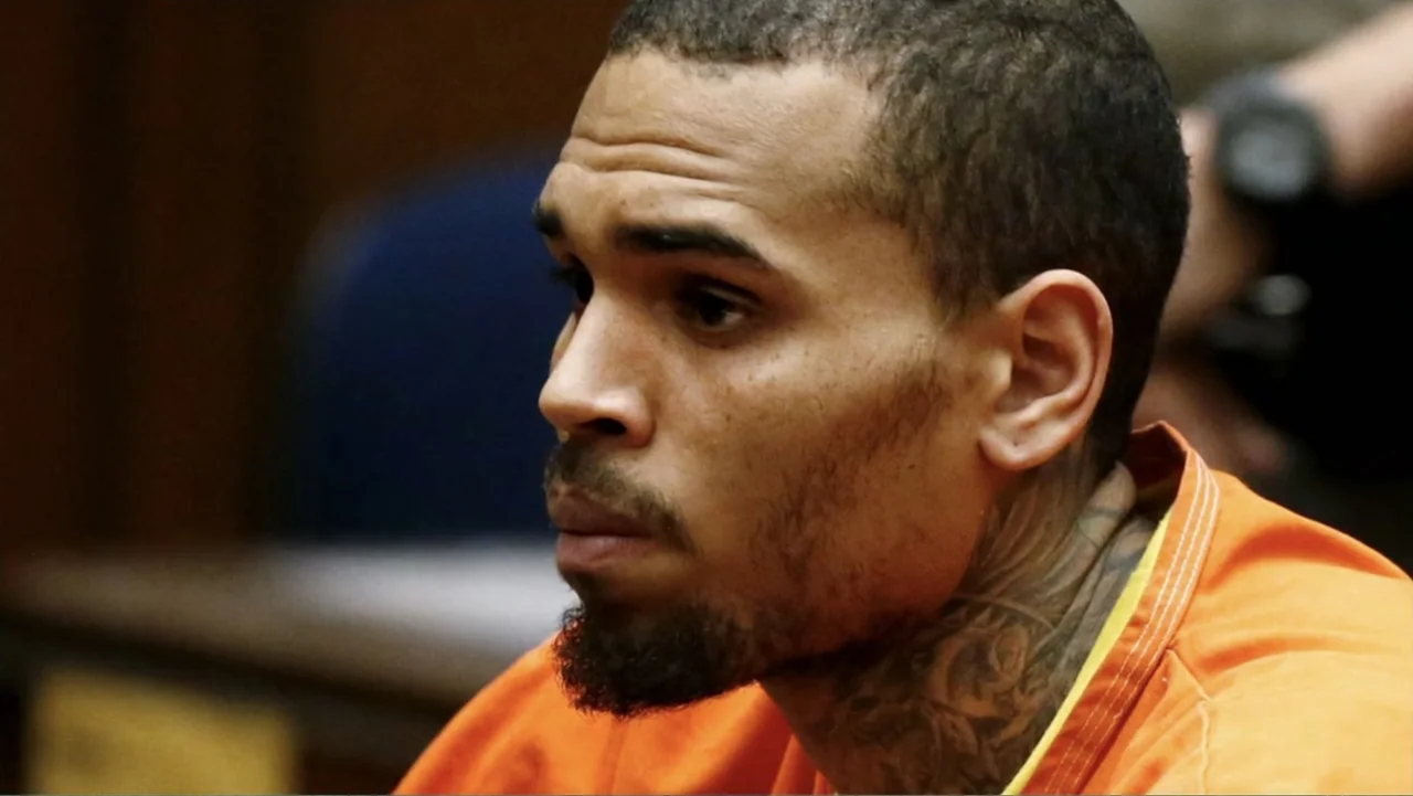 Chris Brown: A History of Violence (2024) movie still: closeup — A courtroom interior with wood paneling visible in the blurred background. A young…