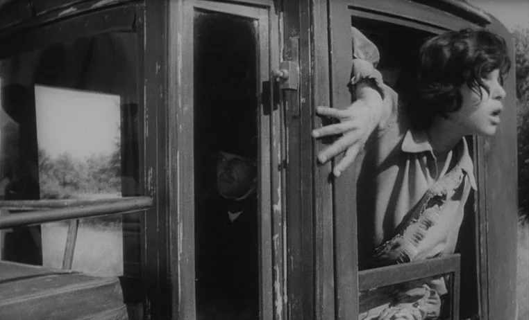The Wild Child (1970) movie still: medium — A wooden passenger carriage moves through a field during the nineteenth century. A young girl leans out…
