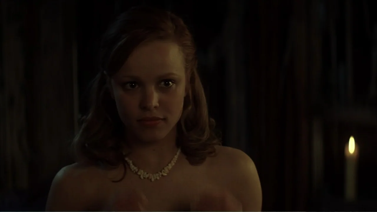 The Notebook (2004) movie still: closeup — A dark indoor space contains a single candle flickering in the blurred background. A young woman faces…