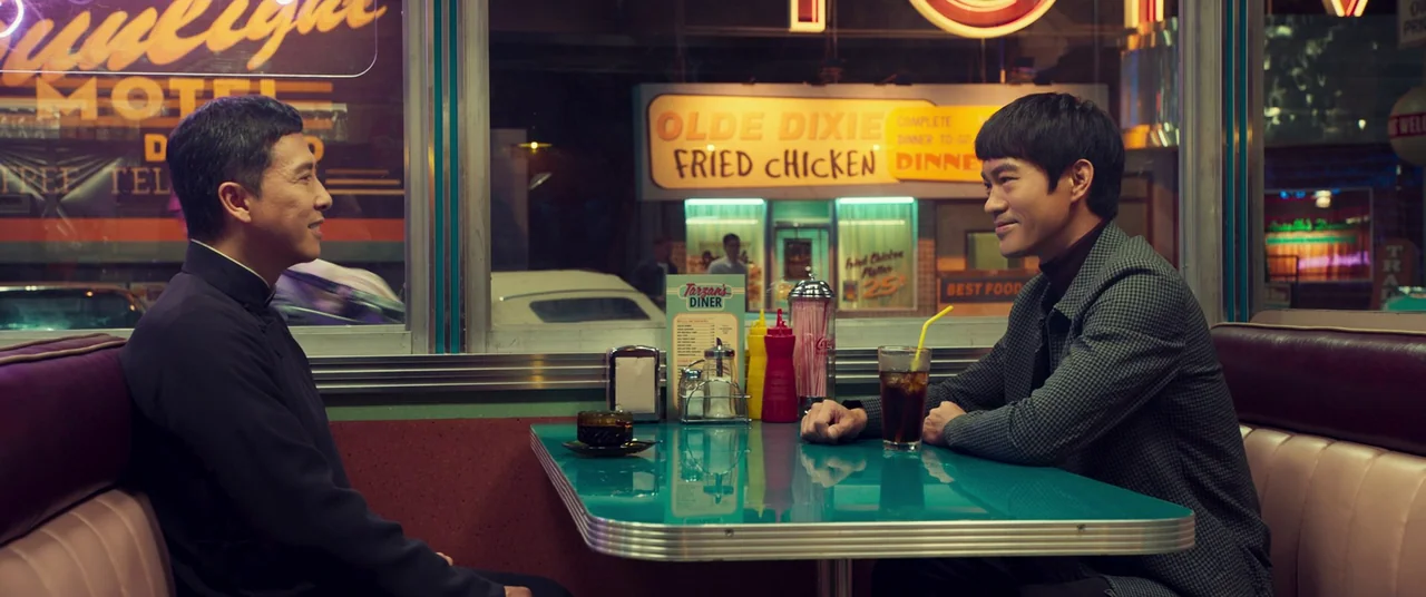 Ip Man 4: The Finale (2019) movie still: medium — A classic retro-style diner booth at night with teal laminate table and vinyl upholstery. Two men…