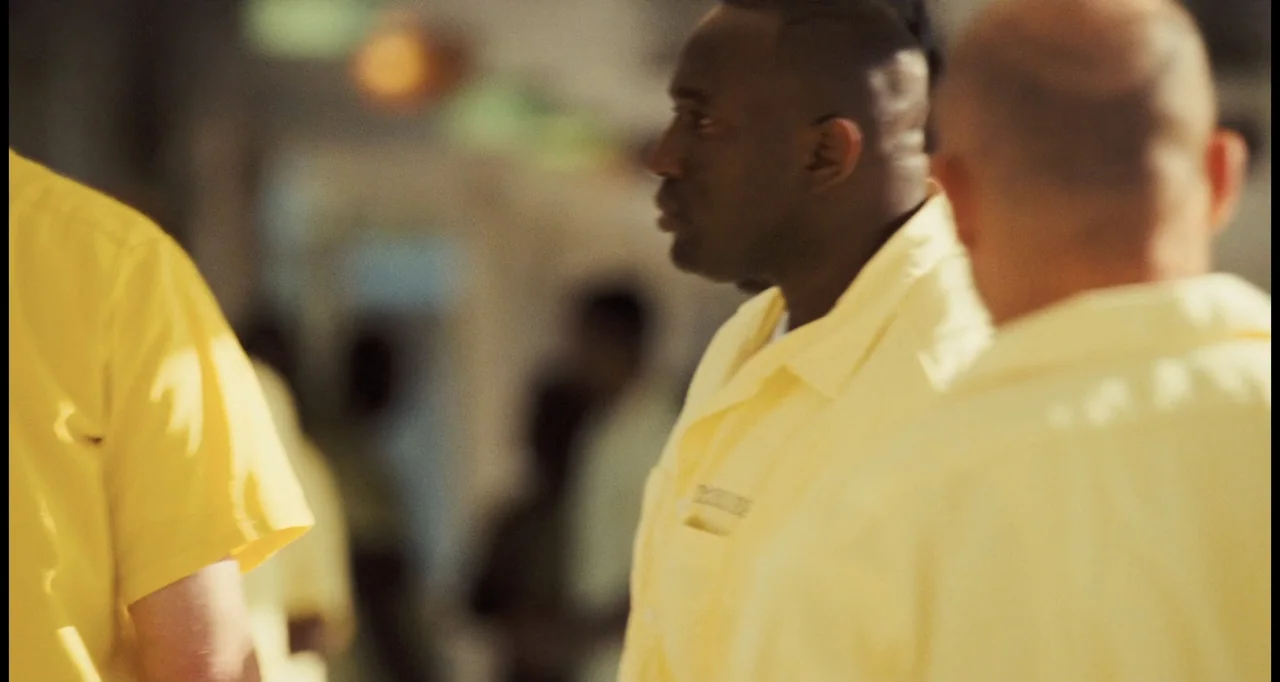 I Love You Phillip Morris (2010) movie still: medium — A brightly lit interior space with individuals dressed in matching yellow attire. Two men…