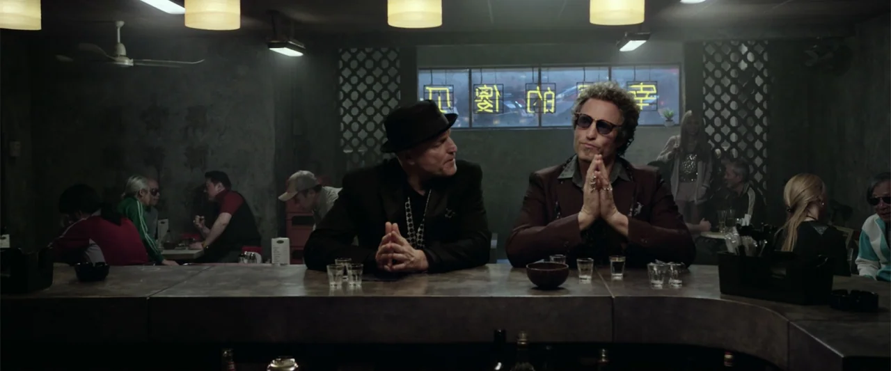 Now You See Me 2 (2016) movie still: medium — A dimly lit bar with concrete walls features a counter where two men sit. The men face the camera…