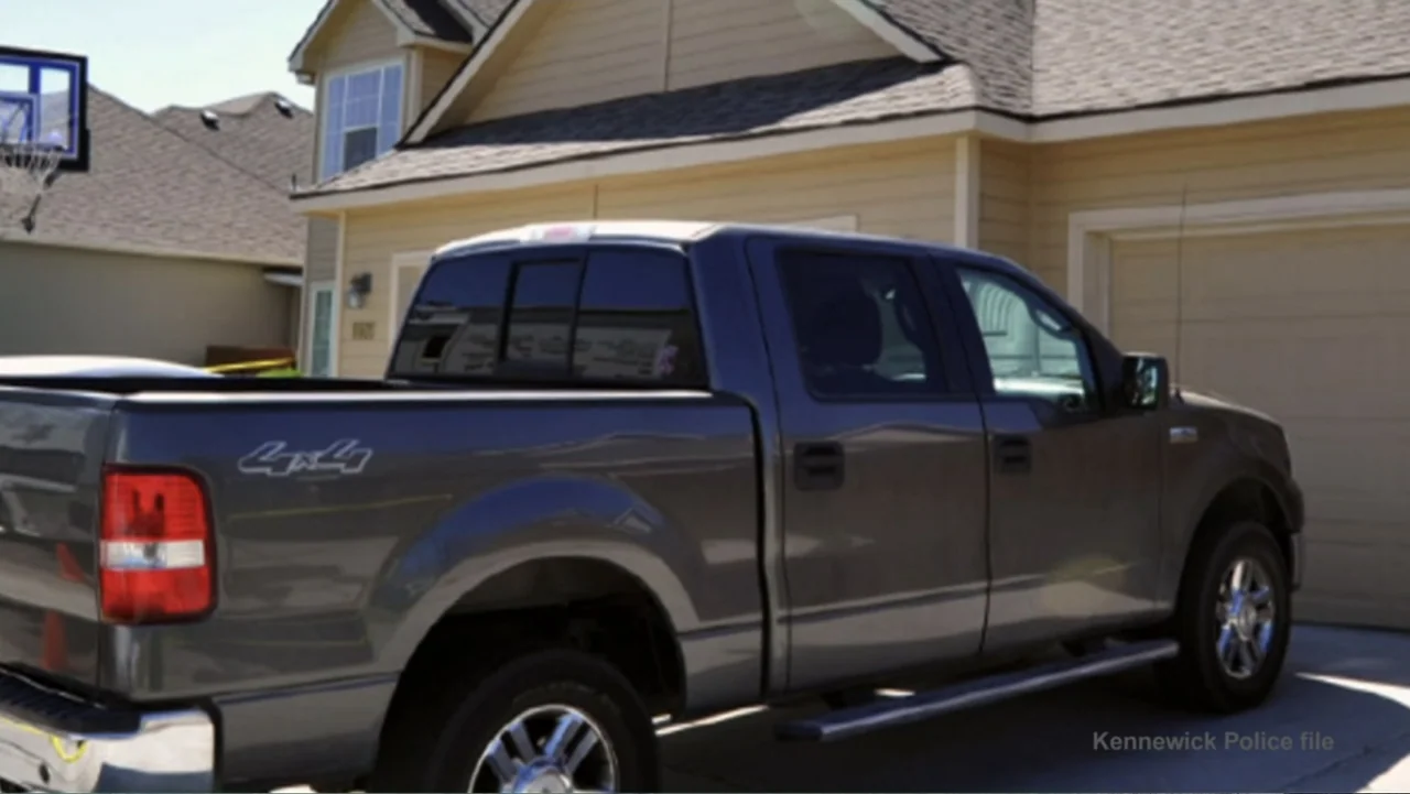 Requiem for the Dead: American Spring 2014 (2015) movie still: medium — A dark gray pickup truck is parked in a suburban residential driveway. A…