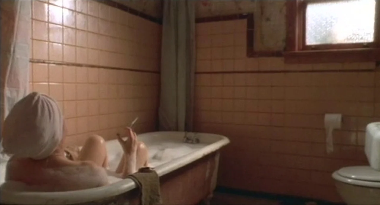 The Annihilation of Fish (1999) movie still: medium — A cramped bathroom features peach-colored square wall tiles and a white porcelain clawfoot…