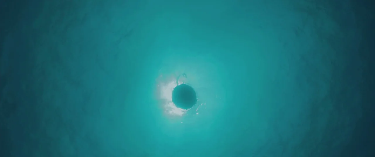All Is Lost (2013) movie still: establishing — Bright sunlight reflects through the rippling surface of clear, deep blue water. The camera is…