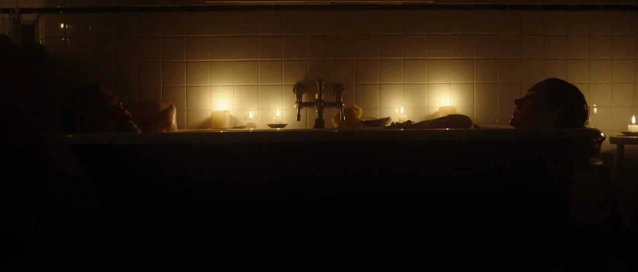 Only The Brave (2017) movie still: medium — A dark, tiled area containing a bathtub with two people submerged in the water. Several lit candles line…
