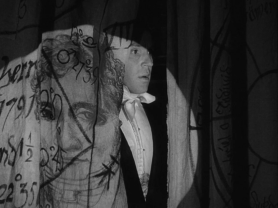 The Magician (1958) movie still: medium — An interior space is divided by hanging curtains decorated with handwritten text and symbols. A man in…