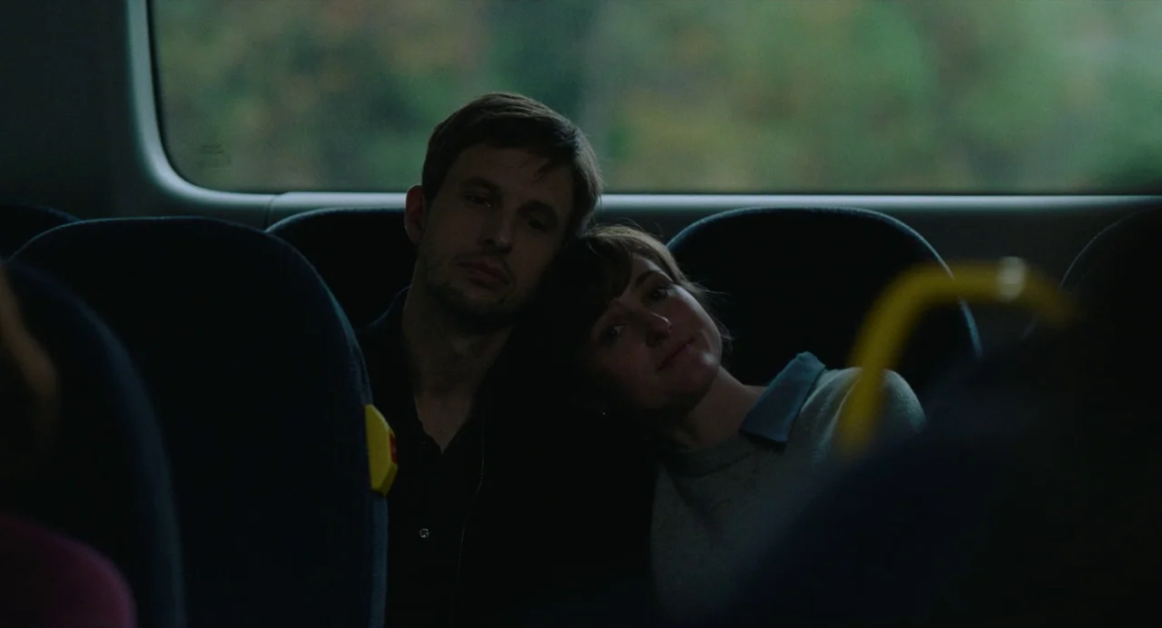 The Worst Person in the World (2021) movie still: medium — Two individuals sit together on a commuter vehicle in front of a large window. A man and…