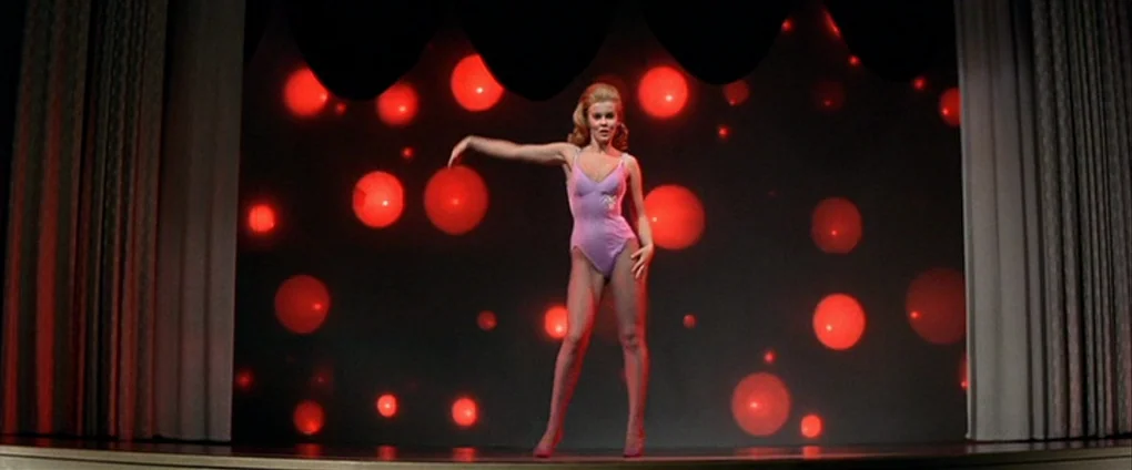 Viva Las Vegas (1964) movie still: fullbody — A dark performance stage features a black backdrop populated by numerous glowing red circles. A blonde…