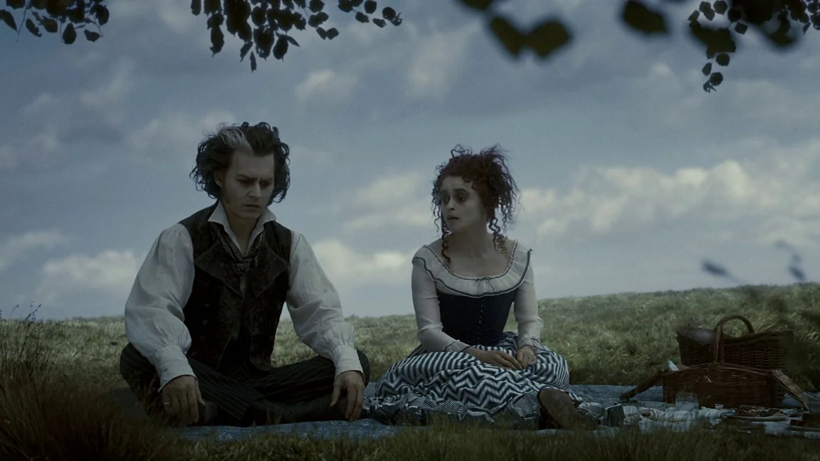 Sweeney Todd: The Demon Barber of Fleet Street (2007) movie still: fullbody — A man and woman sit on a blanket in a vast, greyish-green meadow under…