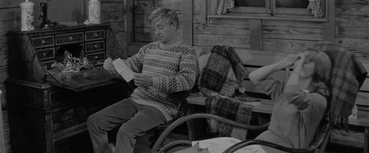 Jules and Jim (1962) movie still: medium — A wood-paneled room features a vintage desk and wooden chairs against a wall. A man in a patterned…