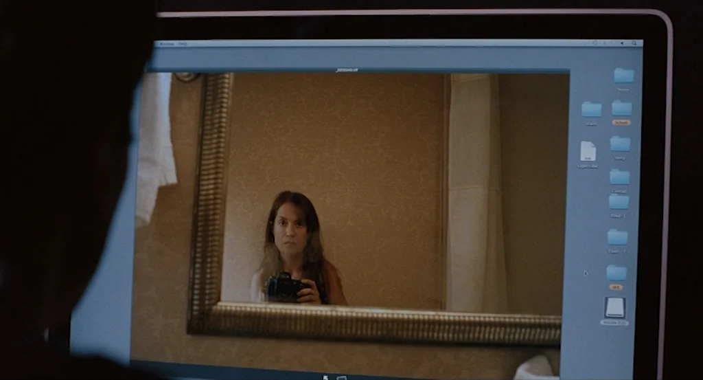 Louder Than Bombs (2015) movie still: medium — A person views a digital image on a computer screen showing a self-portrait reflection. The monitor…