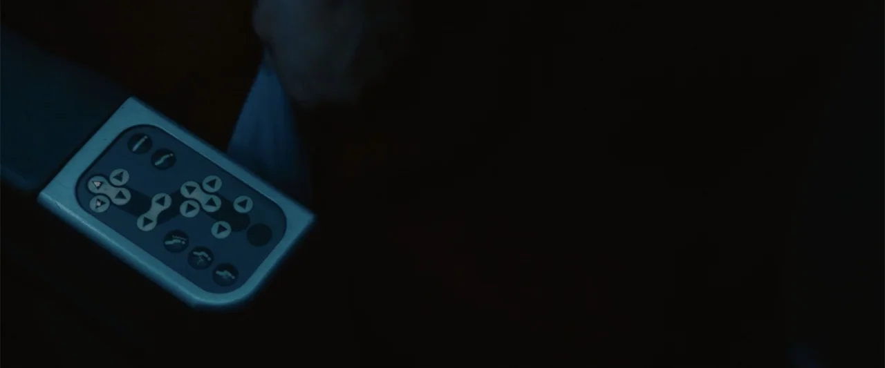 Anyone But You (2023) movie still: closeup — A close-up view shows a plastic airplane seat control panel with multiple buttons. The panel is set…