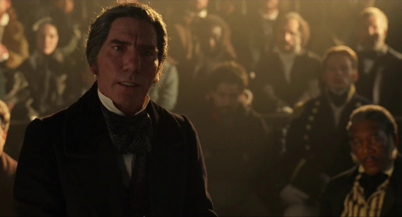 Amistad (1997) movie still: medium — A dark, wood-paneled room serves as an assembly hall with many seated participants. A man in a frock coat…
