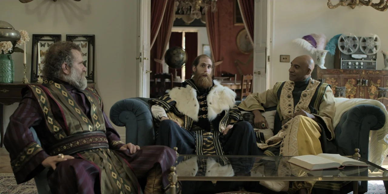 The Three Wise Men: The Truth (2022) movie still: medium — An opulent room with antique furniture and red curtains in the background. Three men in…