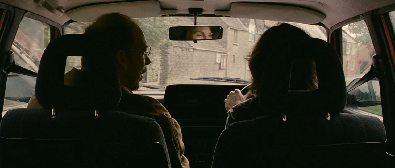 Tamara Drewe (2010) movie still: medium — The interior of a moving vehicle showing the back of the front two seats. Through the windshield and side…