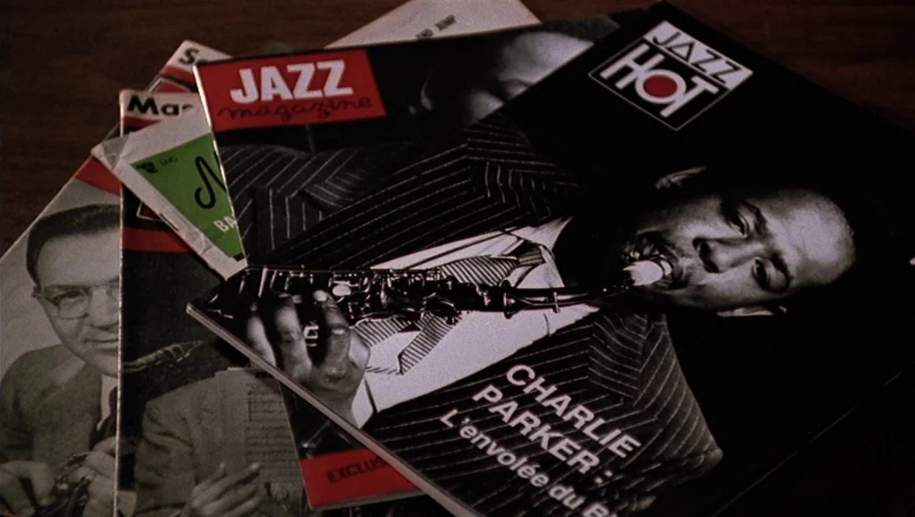 Bird (1988) movie still: closeup — A pile of various music magazines is spread out on a wooden surface. The top magazine features a black and white…