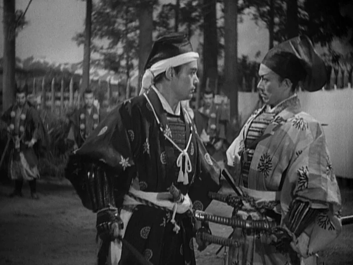 The Men Who Tread on the Tigers Tail (1945) movie still: medium — A group of samurai stands in a dirt field surrounded by tall pine trees. Two…