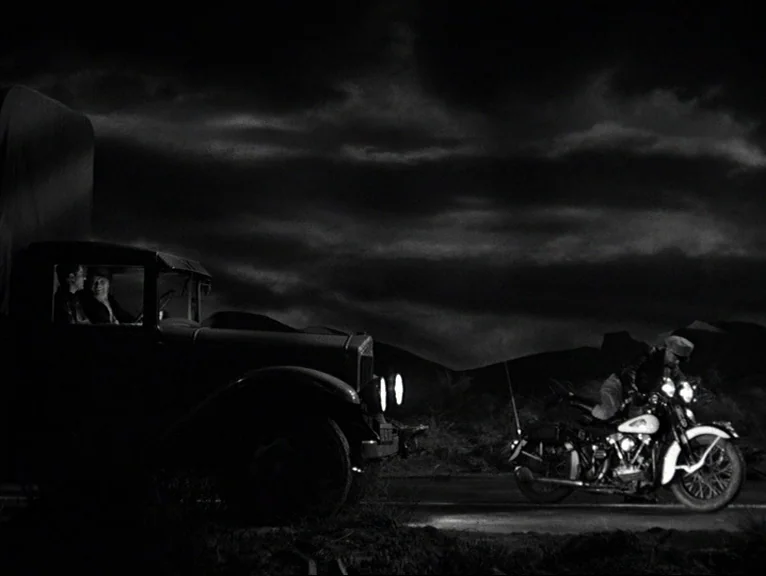Saboteur (1942) movie still: wide — A dark, desolate road at night features a parked truck and a passing motorcycle. The two vehicles are the…