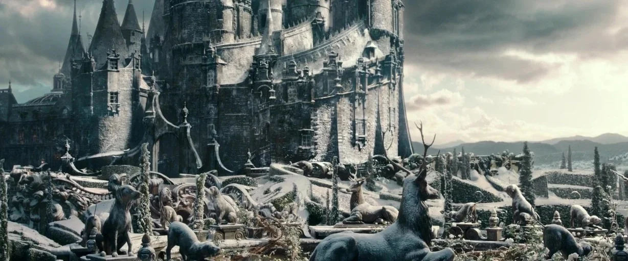 Beauty and the Beast (2017) movie still: establishing — A stone castle with multiple towers and turrets sits in a snow-covered landscape. Stone…