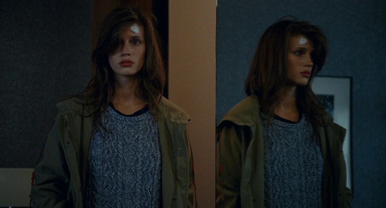 Young & Beautiful (2013) movie still: medium — A dimly lit residential hallway features a large wall mirror reflecting the subject. A woman stands…