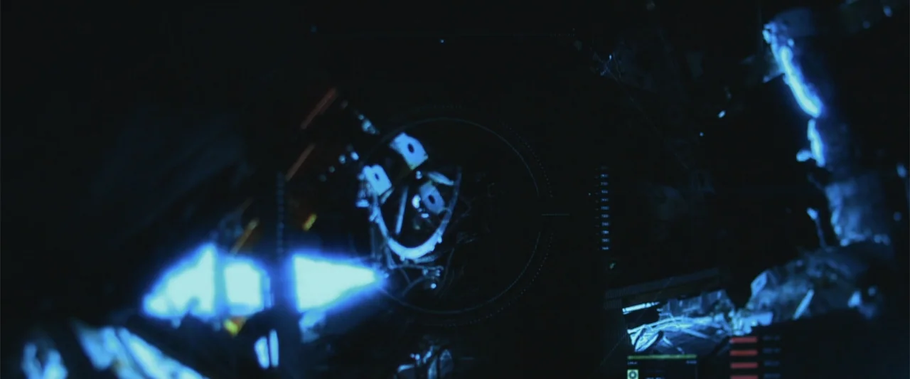 Beyond the Universe (2022) movie still: closeup — A dark interior cockpit features glowing blue instruments and a circular digital display unit. The…