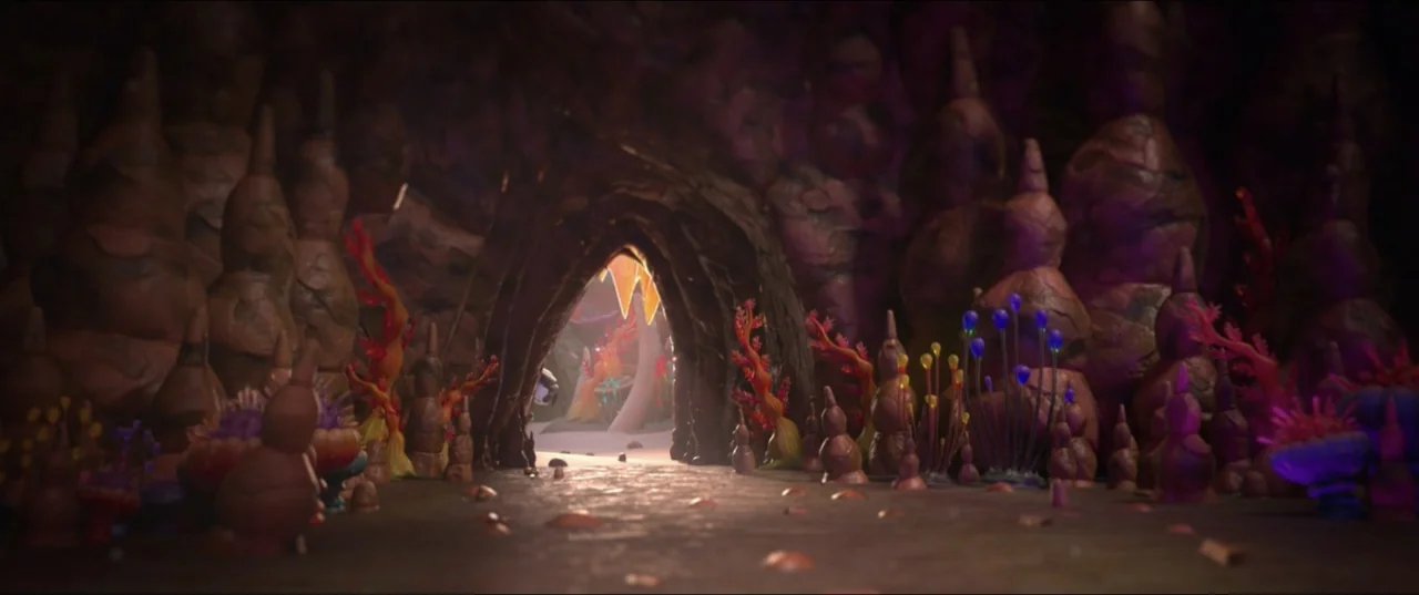 Scarygirl (2023) movie still: establishing — A subterranean cave features dense stalagmites and vibrant, colorful bioluminescent flora throughout. A…