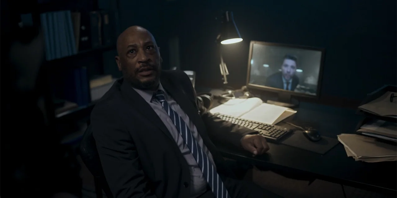 Mi última bala (1998) movie still: medium — A dimly lit office features a desk with a computer monitor and paperwork. A middle-aged man in a suit…