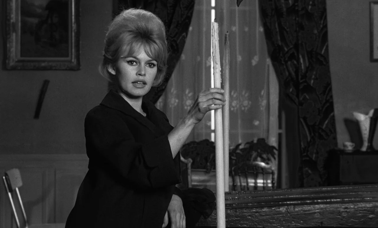 La Verite (1960) movie still: medium — A 1960s interior space featuring a window covered by patterned curtains and a painting. A woman with a…