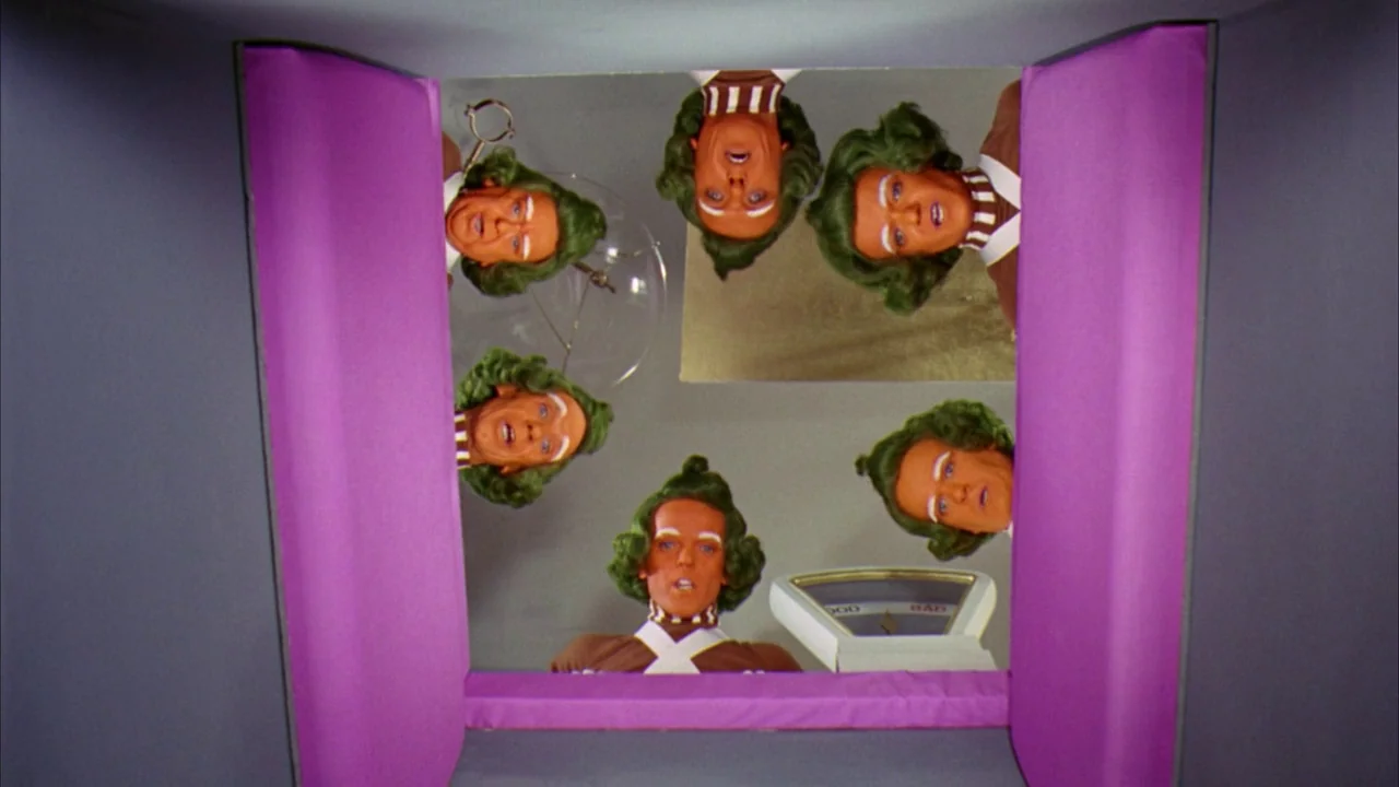 Willy Wonka & the Chocolate Factory (1971) movie still: wide — A square enclosure has bright purple padded walls and a white floor surface. Several…