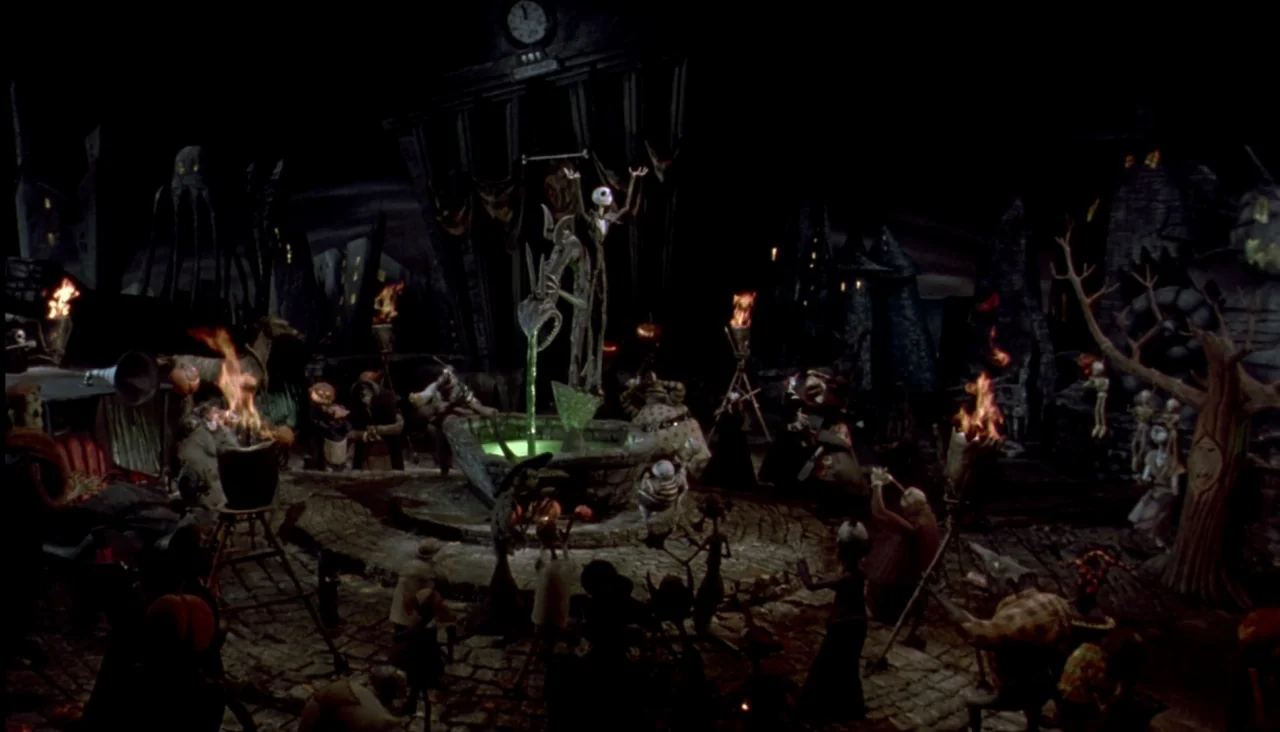 The Nightmare Before Christmas (1993) movie still: wide — A dark, stylized town square with crooked buildings features a central fountain filled…