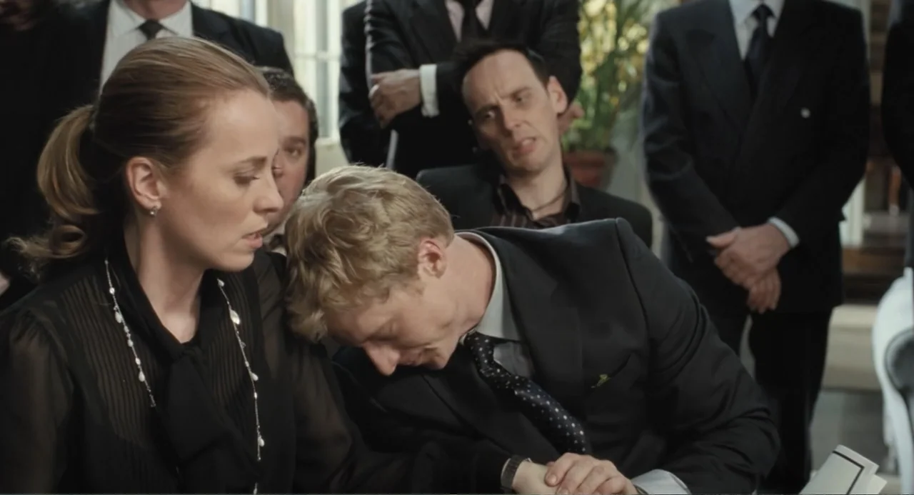 Death at a Funeral (2010) movie still: medium — A crowded room features people in formal business attire attending a solemn gathering. A woman in a…