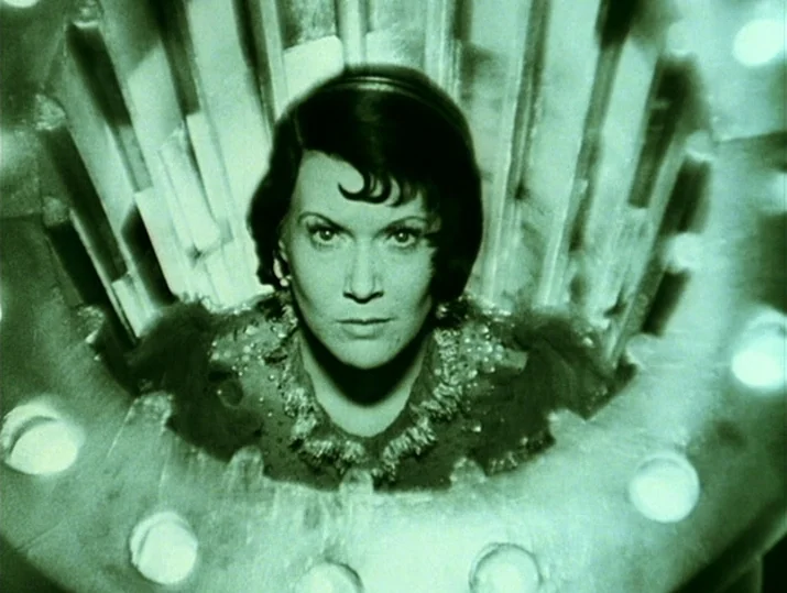 Innocence Unprotected (1968) movie still: closeup — A woman is framed within a cylindrical metallic structure equipped with integrated light bulbs.…