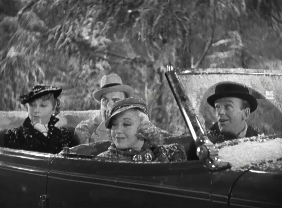 Swing Time (1936) movie still: medium — Four people sit in the open back seats of a moving car during snowfall. Pine trees blur in the dark…