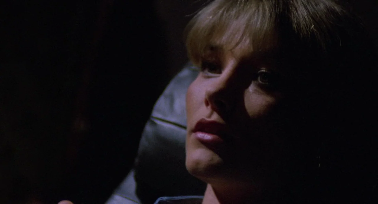 City of the Living Dead (1980) movie still: closeup — A dark, dimly lit car cabin at night provides the setting for the frame. A woman with blonde…