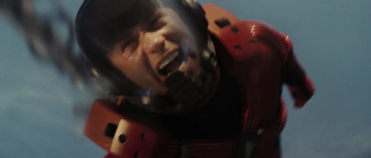 Star Trek (2009) movie still: closeup — A figure in a red pressurized flight suit drifts through deep space. The subject's face is visible through a…