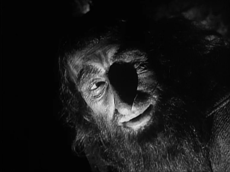 Oliver Twist (1948) movie still: closeup — A dark, cramped interior with rough-hewn stone or natural cave walls. A man with a thick beard and long…