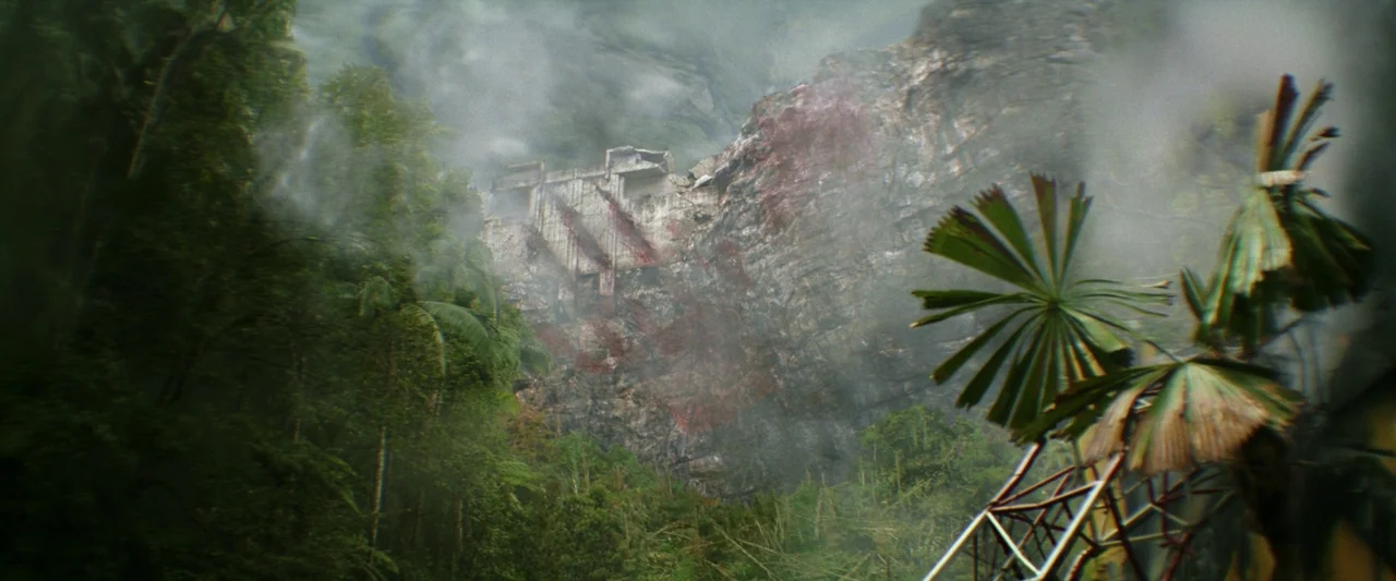 Godzilla x Kong: The New Empire (2024) movie still: establishing — A dense, misty tropical jungle surrounds a massive, ruined concrete structure…