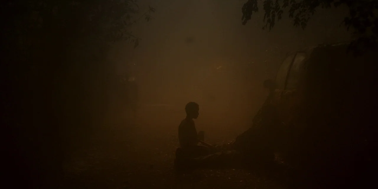 The Girl With All The Gifts (2016) movie still: wide — A dark, hazy outdoor setting at night features heavy atmospheric smoke obscuring distant…