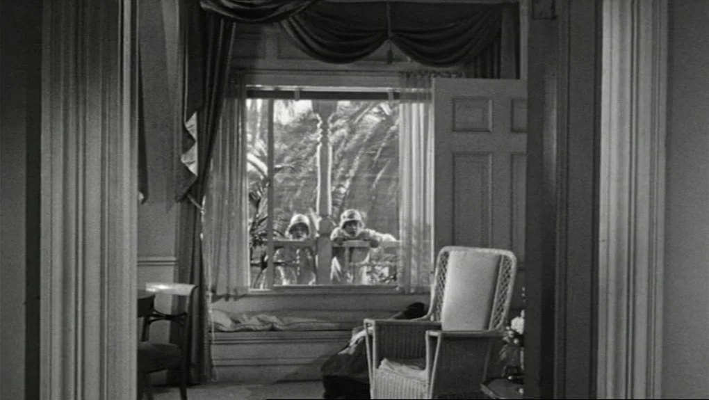 Some Like It Hot (1959) movie still: wide — An interior parlor features a wicker chair and heavy drapes framing a large window. Two children in hats…