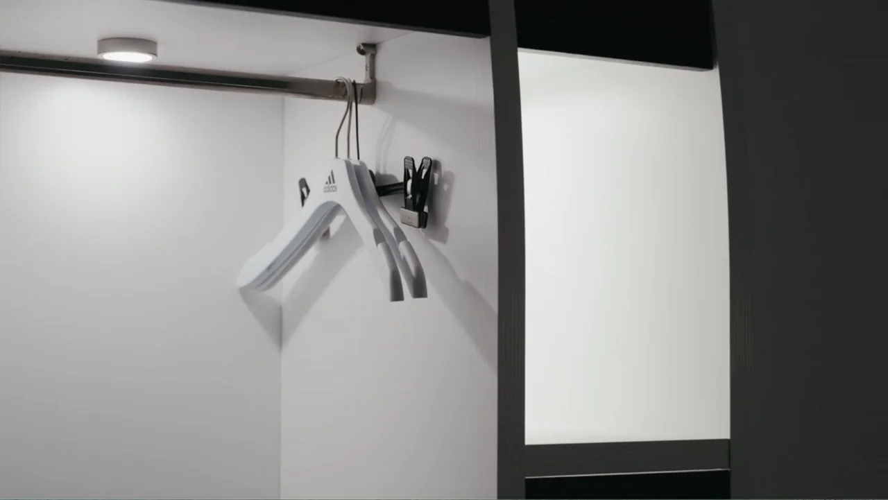 FRAGILE - The story of Nicolò Fagioli (2024) movie still: closeup — A stark white interior of a modern closet with a black frame partition. A single…